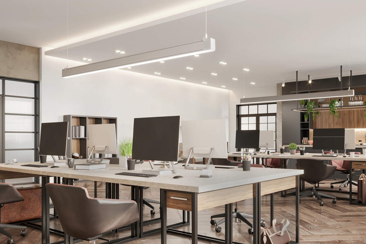 Modern open-plan office layout with desks, computers, and comfortable chairs.
