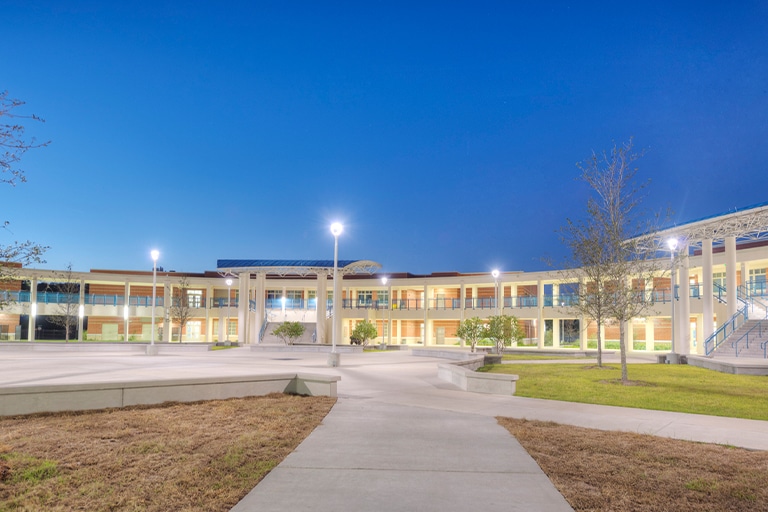 Modern building exterior with courtyard and trees at twilight.